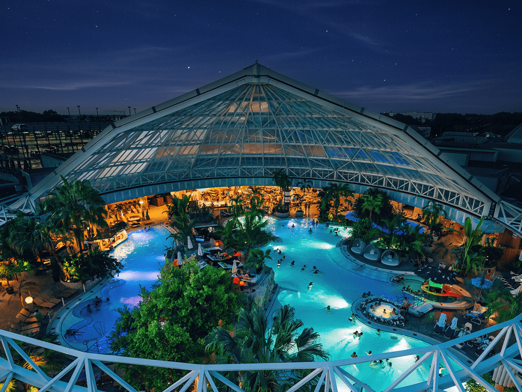Therme Erding bei Nacht – tropisches Badeparadies mit beleuchtetem Innenbereich und Palmen unter Glasdach