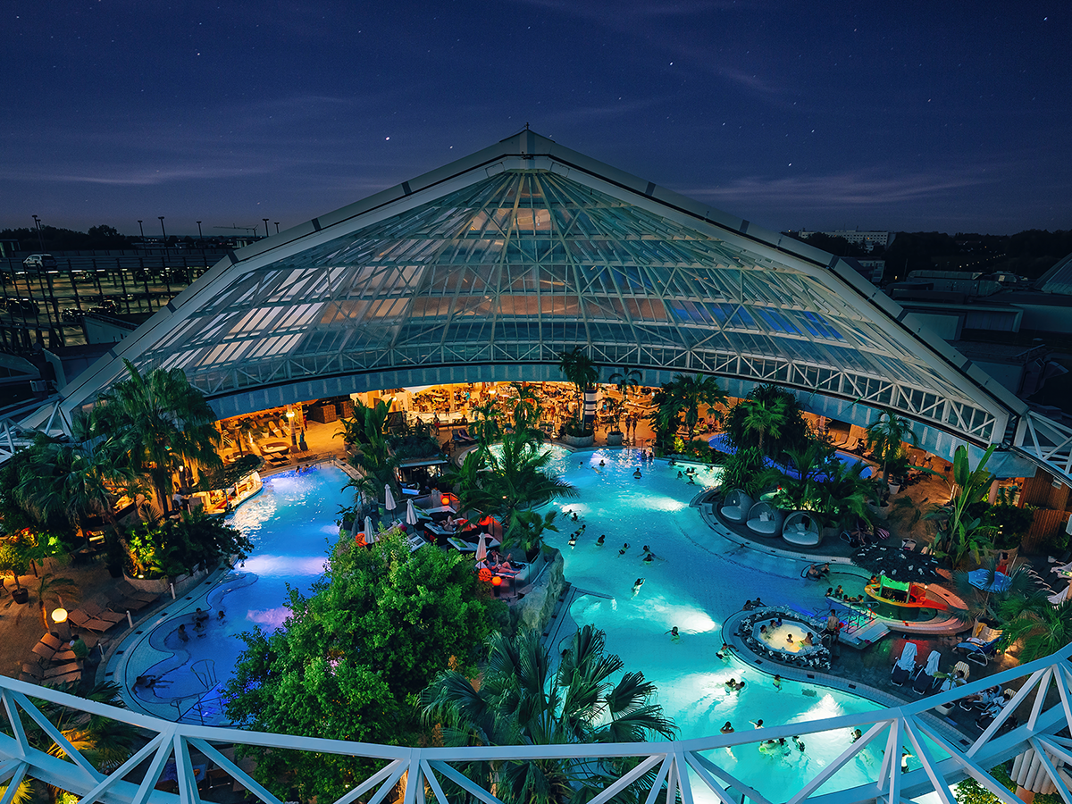 Therme Erding bei Nacht – tropisches Badeparadies mit beleuchtetem Innenbereich und Palmen unter Glasdach